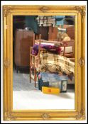 A large antique style contemporary gilt wall mirror with decorative frame having inset bevelled edge