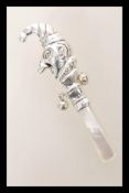 A silver babies / childs rattle toy in the form of Mr Punch having a mother of pearl handle.