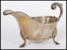 An early 20th century silver hallmarked sauce gravy boat raised on hood feet with acanthus leaf