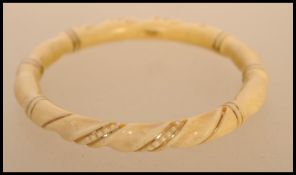 An early 20th century ivory and gold banded bangle. The carved bangle having twist design with