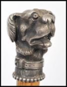 A 20th Century walking cane, the Malacca stick surmounted with a white metal cast figural dog.