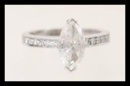 A stamped 750 white gold ring set with a marquise cut diamond and channel set brilliant cut diamonds