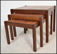 A 1970's Danish influence teak wood and tile top nest of graduating tables being raised on shaped
