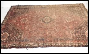 An early 20th century Persian Bokhara rug having red ground with black borders and central panel