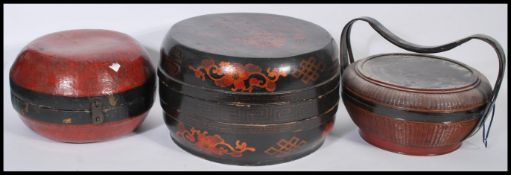 A collection of three Chinese lidded Lacquered food carriers, the largest with removable lid and