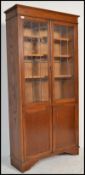 A 1920's oak library bookcase cabinet being raised on bracket feet with a twin door cupboard beneath