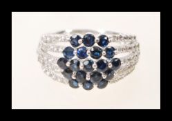 A stamped 14ct white gold sapphire and diamond cluster ring having a split shank design. Size N.5.