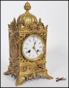 A 19th century French gilt brass mantel clock having grotesque face masks and pineapple finials. The