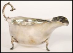 An early 20th century silver hallmarked sauce gravy boat raised on hoof feet with flared rim and