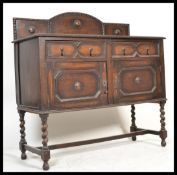 A 1920's oak Jacobean revival sideboard dresser being raised on bobbin turned legs having twin