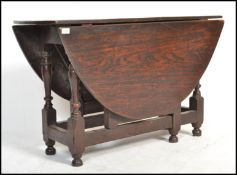 An 18th century solid country oak peg jointed drop leaf / gate leg dining table being raised on