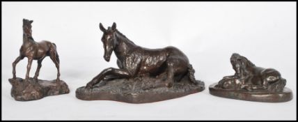 A collection of three bronzed effect sculptures modelled as horses / foals, to include a recumbent