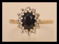 A hallmarked 9ct gold sapphire and diamond cluster ring having a central oval blue sapphire