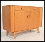 A mid century oak sideboard being raised on tapering legs with short drawers over cupboards beneath.