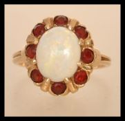 A marked 14ct gold opal cluster ring having a central opal panel with a halo of orange stones.