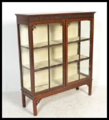 An Edwardian mahogany display cabinet vitrine being raised on squared legs with a fret pierced