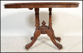 A Victorian 19th century walnut and marquetry inlaid breakfast / loo table being raised on splayed