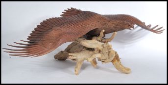 A large 20th century fantastic detailed carved sculpture of an eagle raised on naturalistic wooden