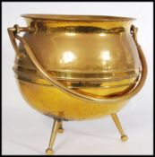A 19th century Victorian large brass cauldron raised on three bun feet and tapering legs. Swing