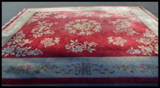 A 20th Century vintage floor rug / mat of large proportions on red ground, central panel with
