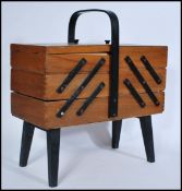 A vintage retro 20th century teak wood metamorphic sewing box raised on ebonised supports complete