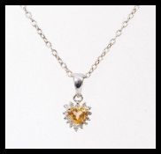 A stamped 14ct white gold pendant set with a heart shaped citrine and diamond accent stones, on a