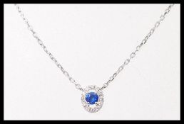 An 18ct white gold pendant set with a brilliant cut central sapphire with a halo of accent diamonds,