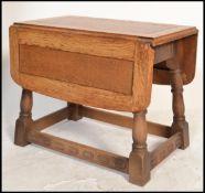 A vintage 20th century Ercol carved oak drop end leaf coffin / coffee table raised on turned legs.