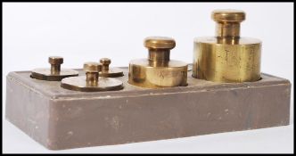 A set of early 20th Century graduating brass weights in a fitted stand weighing from 1kg to 5g.