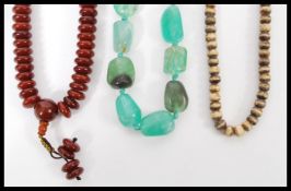 A group of three vintage necklaces to include a large green quartz jade type necklace, a cherry