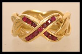 A hallmarked 18ct gold band ring set with round cut rubies in a kiss motif . Marked ©FM88. Import