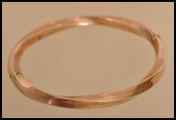 A 9ct gold bangle bracelet of twist form having a hidden clasp. Weighs 13 grams.