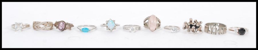 A collection of 11 silver rings to include white stone, onyx, blue stone, opal, purple stone etc.