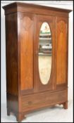 An Edwardian mahogany inlaid  single wardrobe being raised on a plinth drawer base with central
