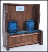 A 20th century apprentice piece hall settle bench of oak construction having loose cushion. 17cm