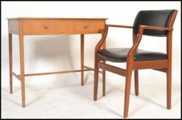 A 1970's teak wood desk with squared legs, pedestal of drawers and a teak wood open armed office