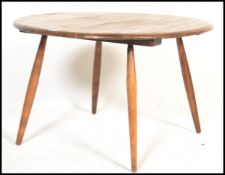 A mid century Ercol circular coffee table being raised on turned tapering legs with chamfered edge