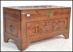 A mid 20th century Chinese camphor wood blanket box chest with carved, detailed scenes in relief