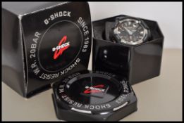 A casio G-Shock 20 Bar shock resist wrist watch having a large round face with pierced hands and