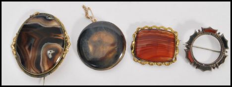 A collection of four 19th Century polished stone brooches set within silver white metal mounts.