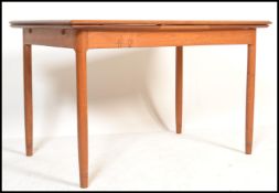 A 1970's teak wood extending dining table being raised on turned legs with extending frieze frame.