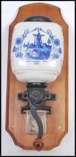 A vintage 20th Century wall mounted coffee grinder having a delft blue and white windmill pattern to
