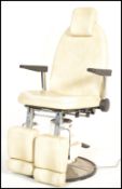 A retro 20th Century Dental / Dentist adjustable chair, white faux leather upholstery raised on a