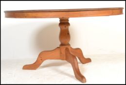 A 20th Century pine dining table having a circular top raised on a central turned column above three