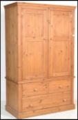 An antiques style large country pine double wardrobe. Raised on a plinth base with drawers having