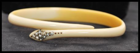 A Victorian carved ox bone snake bangle with paste set head. Diameter approx 3 1/4 inches.