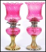 A pair of 19th Century Victorian oil lamps having cranberry glass shades with fanned rims and