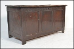 An 18th century oak coffer, the hinged plank top with steel strap hinges over single panel sides and