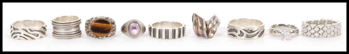 A selection of silver rings to include a band ring prong set with a white stone, a bark effect