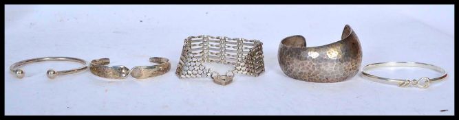 A selection of silver jewellery to include a twist design bangle, a hammered bangle, a heart lock